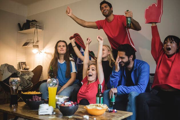 Multi-ethnic friends watching sport while sitting on sofa at home , model released, property released Copyright: xMaskotx , MA77408