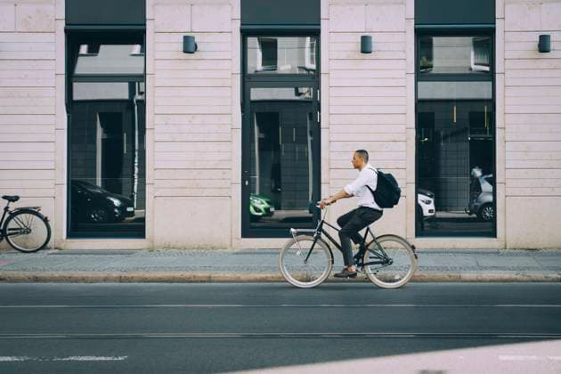 IMAGO Creative: Menschen in Berlin Full length of businessman riding bicycle on street against building in city , model released Copyright: xMaskotx , MA77433