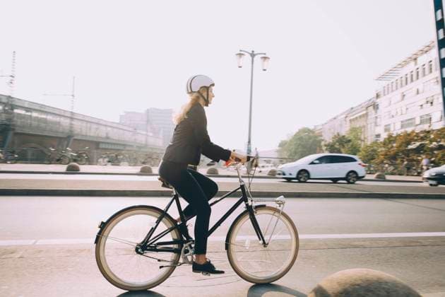 IMAGO Creative, Urban Lifestyle Full length of female executive wearing helmet riding bicycle on road in city , model released Copyright: xMaskotx , MA77491
