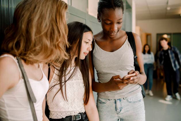 Junior high students using smart phone while standing in school corridor , model released, property released Copyright: xMaskotx , MA77597