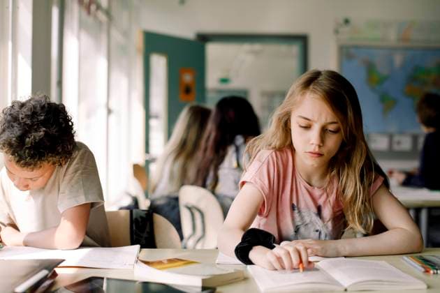 IMAGO Creative: Bildung, Schreiben Female student studying from book while sitting by male friend in classroom , model released, property released Copyright: xMaskotx , MA77636