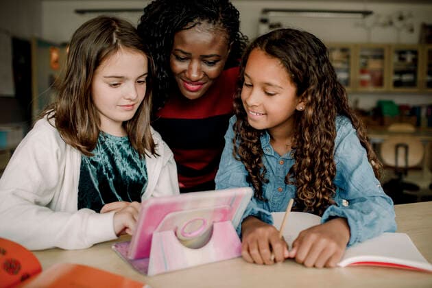 Female tutor with students looking at digital tablet in classroom , model released, property released Copyright: xMaskotx , MA77653