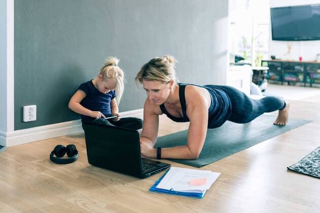 IMAGO Creative: Internationaler Frauenmonat, Gesundheit, Frauen in der Menopause Mother looking at laptop and doing planks while daughter using smart phone in living room , model released, property released Copyright: xKentarooxTrymanx , MA77717