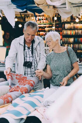 Senior man showing pattern on fabric to woman while shopping at market in city , model released Copyright: xMaskotx , MA78058