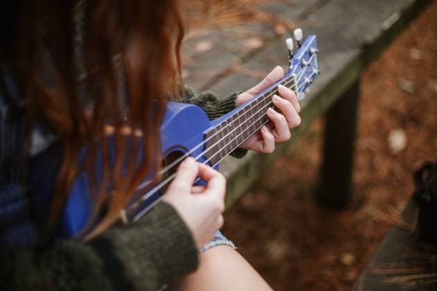 IMAGO Creative: Digitale Welt, Verzicht auf Technologie From above unrecognizable brunette in casual clothes playing small blue guitar while sitting alone on wooden bench in autumn city park Copyright: xJoaquinxMartinezx Model Released