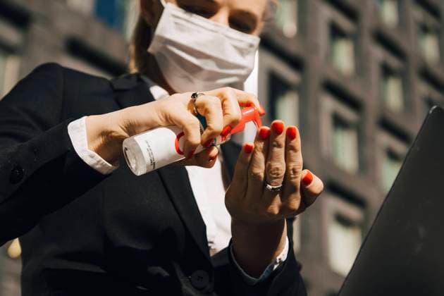 Businesswoman with face mask using hand sanitizer , model released Copyright: xMaskotx , MA78532