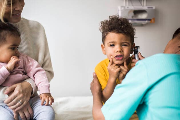 Portrait of boy making faces during ear examination by female doctor in clinic , model released, property released Copyright: xMaskotx , MA78675