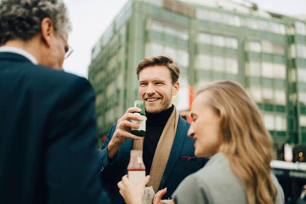 IMAGO Creative: Corporate: Klimaschutz, Digitalisierung und Urbanisierung Smiling male entrepreneur with drink looking at coworkers in city Germany, Hamburg, model released Copyright: xMaskotx , MA79088