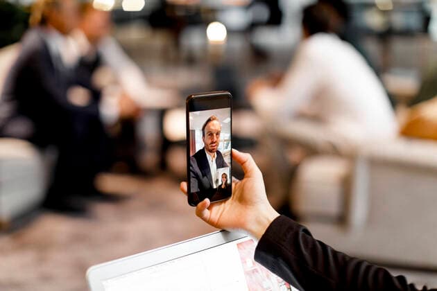 Male and female colleagues talking through video conference on smart phone in office Sweden, Stockholm, model released, property released Copyright: xMaskotx , MA79488