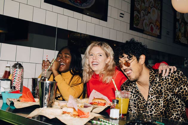 Portrait of happy woman with friends eating burger during social gathering at cafe Sweden, Stockholm, model released, property released Copyright: xMaskotx , MA79652