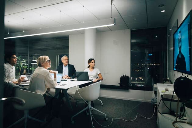Colleagues looking at businessman during video conference meeting at night in office Sweden, Stockholm, model released, property released Copyright: xMaskotx , MA79677