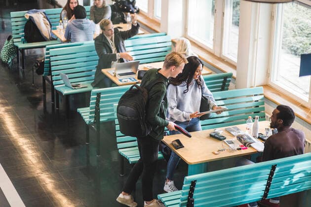 Male and female students talking with friend sitting at table in cafeteria Sweden, Stockholm, model released, property released Copyright: xMaskotx , MA79888