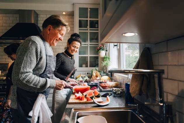 Smiling senior male and female friends cutting fruits at kitchen counter Sweden, Stockholm, model released, property released Copyright: xMaskotx , MA80034