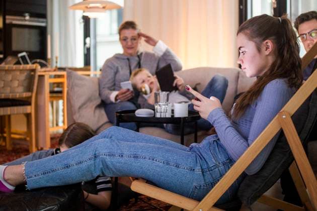 IMAGO Creative: Jahreszeit Winter, Couching Teenage girl using smart phone while relaxing with family in living room at home Sweden, Stockholm, model released, property released Copyright: xMaskotx , MA80372