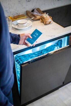 Cropped image of man using mobile app while standing by dishwasher at smart home Sweden, Stockholm, model released, property released Copyright: xMaskotx , MA80398