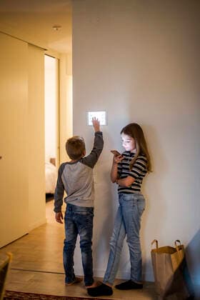 Brother using digital tablet mounted on wall while sister text messaging on mobile phone in smart home Sweden, Stockholm, model released, property released Copyright: xMaskotx , MA80402