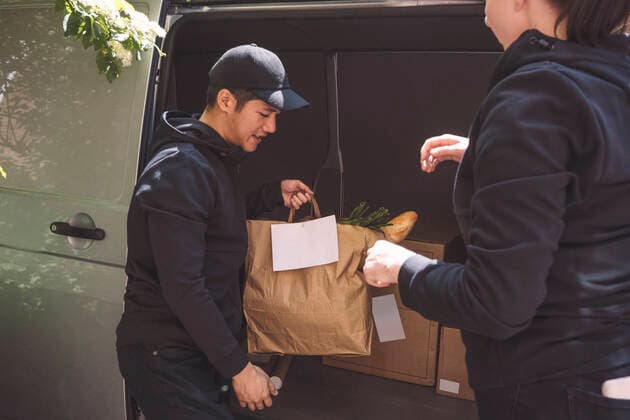 Delivery man talking to female colleague while holding package near truck Sweden, Stockholm, model released Copyright: xMaskotx , MA81134