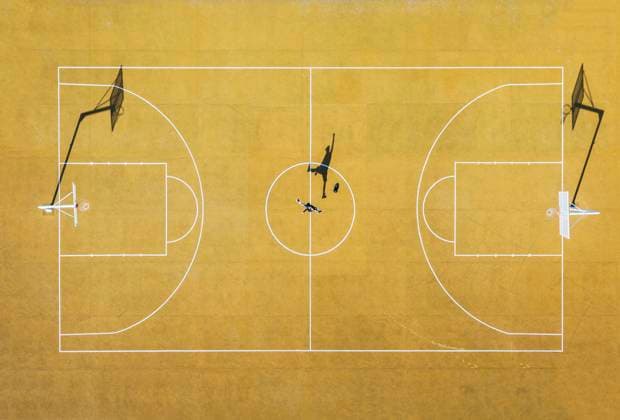 IMAGO Creative: Sport in der Stadt Young man playing basketball on outdoor court. Top view, bird eye view of yellow basketball court Copyright: xJosexLuisxCarrascosax Model Released