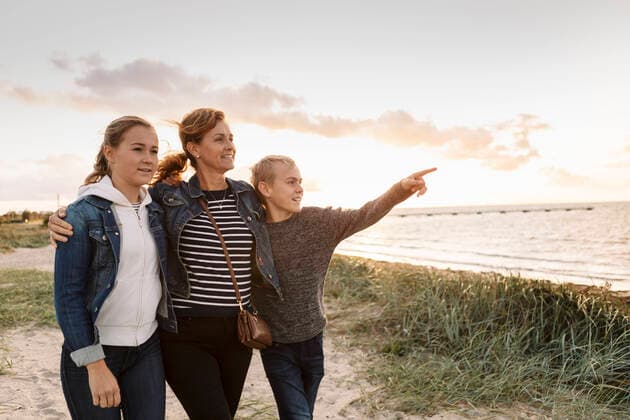 IMAGO Creative: Internationaler Frauenmonat, Gesundheit, Frauen in der Menopause Smiling son pointing while mother and daughter standing against cloudy sky at beach Sweden, Malmo, model released Copyright: xKentarooxTrymanx , MA81214