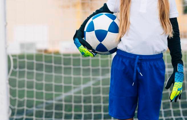 Crop girl in white and blue uniform with soccer ball while standing alone on green field in modern sports club, Model released Copyright: xJosexLuisxCarrascosax MR