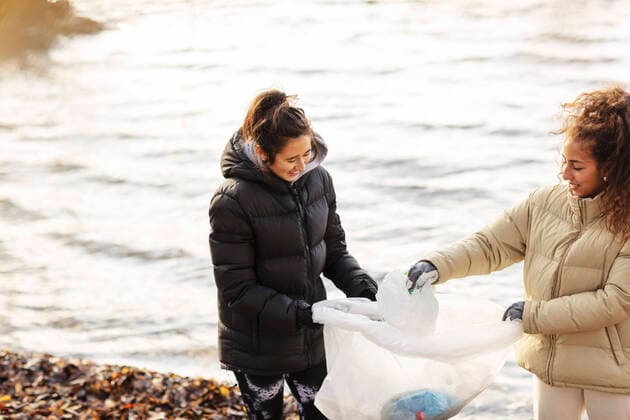 Smiling female environmentalists collecting microplastics against lake Sweden, Stockholm, model released Copyright: xMaskotx , MA81988