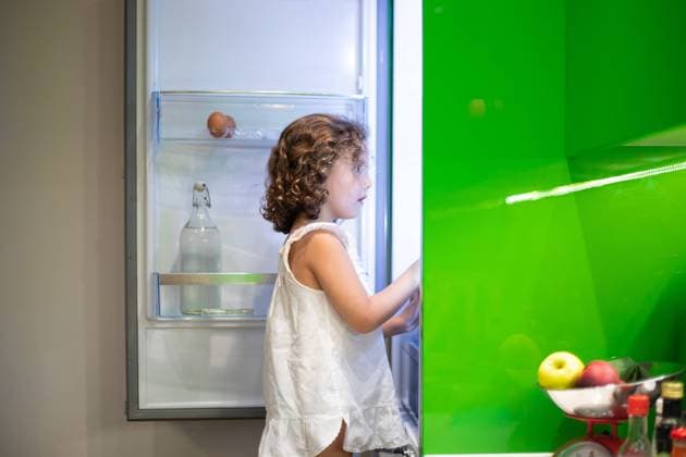 IMAGO Creative: Gesellschaft, Armut Little girl in sleepwear searching for snack inside open refrigerator at night in kitchen at home Copyright: xJosxTempranox Model Released