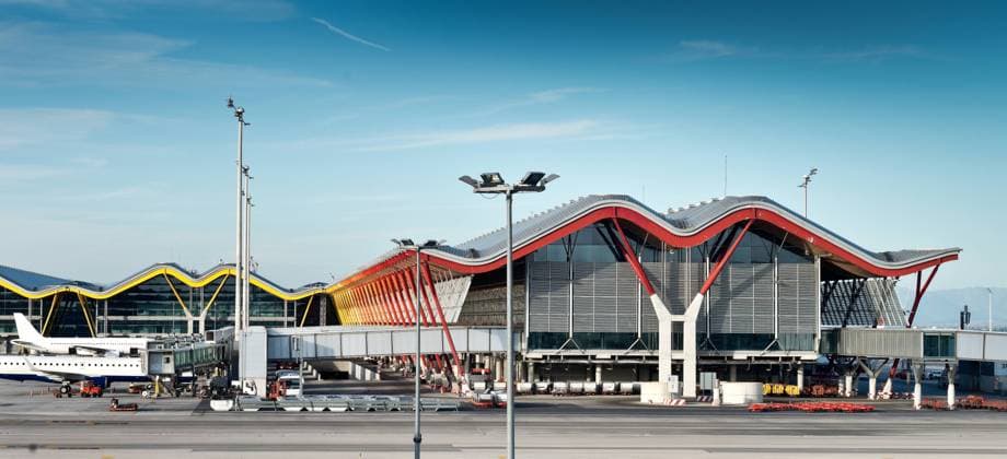 Unusual facade of Madrid Barajas airport with wavy roof and vivid yellow pillars in composition with window walls under blue sky in Spain Copyright: xKavixSanchezx Model Released