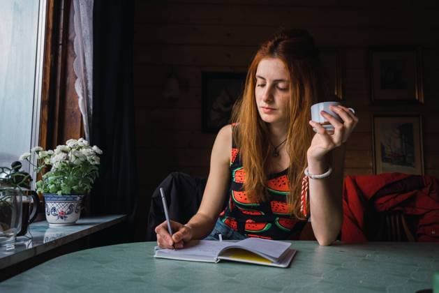 IMAGO Creative, Lifestyle, Tik Tok-Trend thatgirl Adult woman thinking while sitting at table in cozy room and writing in notebook, Model released Copyright: xKikexArnaizx MR