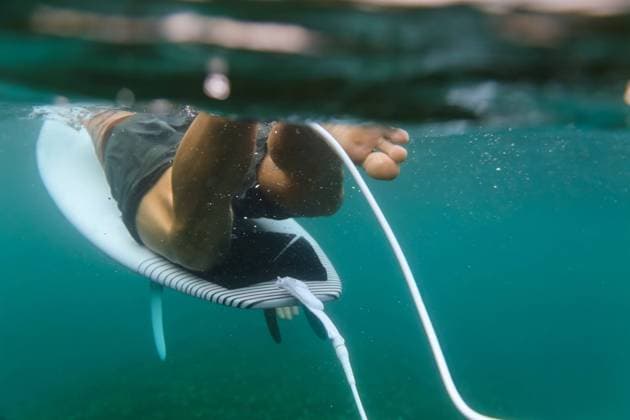 Back view of crop male floating on surf board in azure water of sea on Bali, Indonesia Copyright: xKonstantinxTrubavinx Model Released