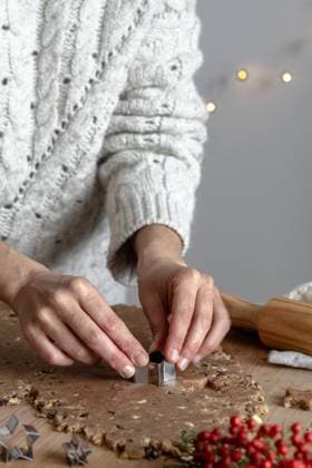 Crop hands of faceless woman making gingerbread cookies with tin form in shape of star in kitchen Copyright: xLeirexGamboax Model Released