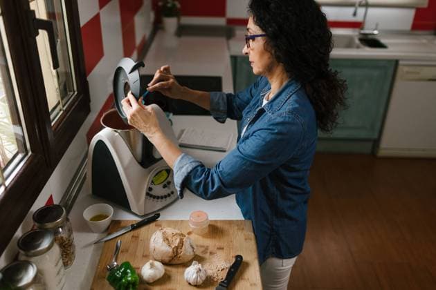 IMAGO Creative: Veganuary, fleischlos leben IMAGO Creative: 2021 Trends Middle-aged woman introducing a few ingredients in the Kitchen Robot Copyright: xLightsyx Model Released