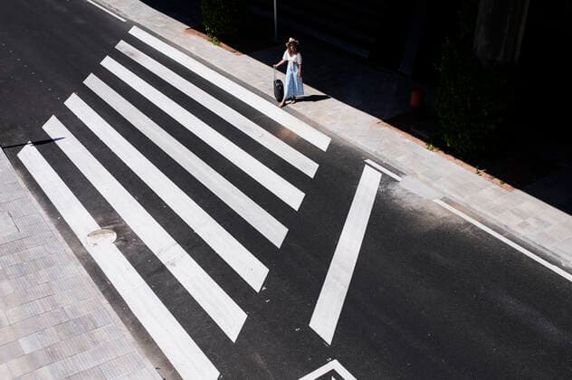 Top view of young woman with baggage crossing a street at the airport model released Symbolfoto IGGF01340