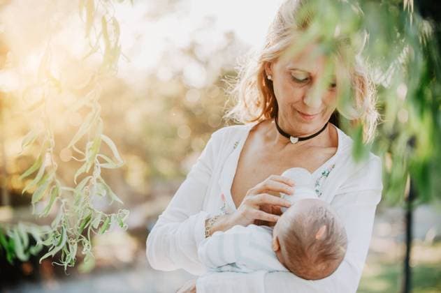 woman feeding a baby with a bottle in the park, Model released Copyright: xLuciaxVargasx MR