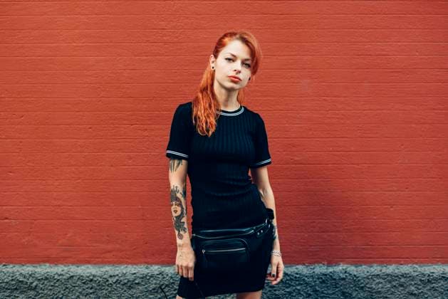 Portrait of red-haired tattooed woman standing at a brick wall model released Symbolfoto JSMF01262