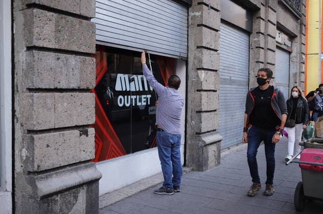 (201219) -- MEXICO CITY, Dec. 19, 2020 -- A man closes the roll-up door of a shop in Mexico City, Mexico, on Dec. 18, 2020. Mexican authorities said on Friday that they would re-impose lockdown measures in Mexico City and the State of Mexico amid surging COVID-19 cases and hospitalizations. (Photo by Xinhua) MEXICO-MEXICO CITY-COVID-19 SunnyxQuintero 