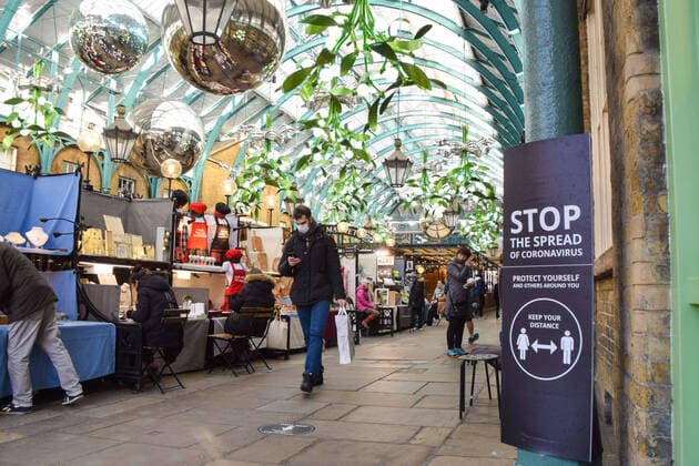 December 19, 2020, London, United Kingdom: A man wearing a face mask as a precaution against the spread of covid-19 walks past a Stop The Spread Of Coronavirus sign in Covent Garden Market. London United Kingdom - ZUMAs197 20201219_zab_s197_002 Copyright: xVukxValcicx