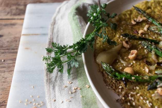 Top view of white plate with oat crepe with asparagus and tahini paste served on rustic board with greens Copyright: xOlgaxVilax Model Released