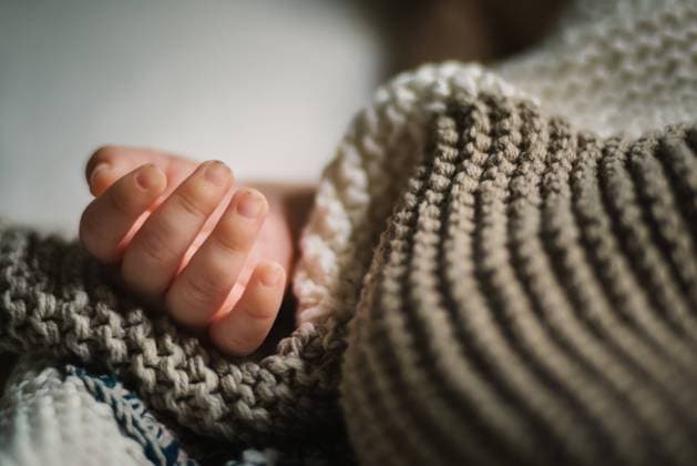 IMAGO Creative: Gesundheit, Stille Closeup hand of anonymous sleeping baby lying under soft knitted blanket in nursery Copyright: xPatriciaxBecarotox Model Released