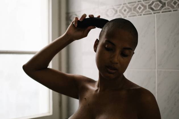 IMAGO Creative: Brustkrebsmonat Focused African American female in lingerie standing in bathroom and using trimmer for cutting hair Copyright: xPerexNadalx Model Released