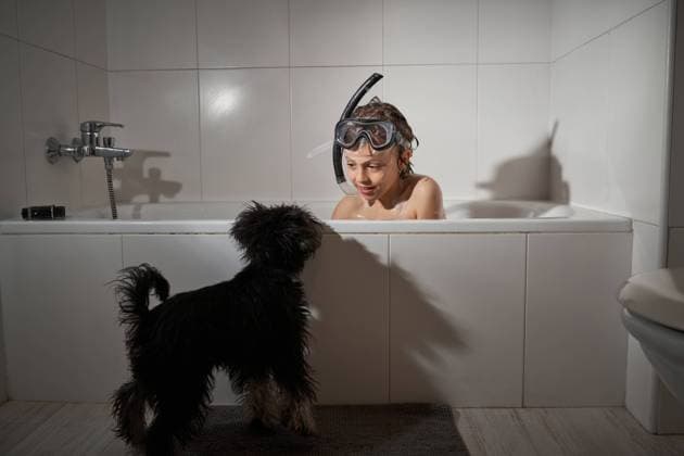 Cheerful happy boy showering with his dog in the bathtub at home playing and using a snorkel mask Copyright: xPhilippexDegrootex Model Released