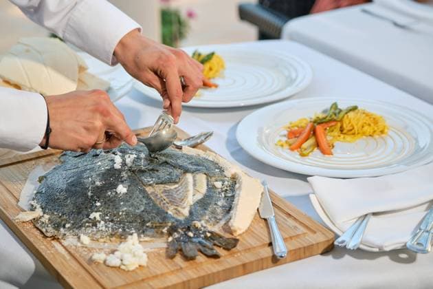 Closeup of yummy juicy aromatic fish baked in salt dough crust being served by anonymous chef in restaurant, Model released, Property released Copyright: xPhilippexDegrootex MR