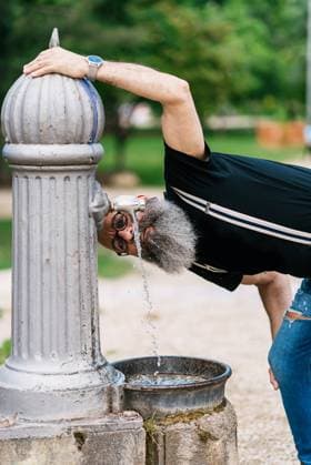 IMAGO Creative, Jahreszeit Sommer, Sommer in der Stadt Content old male hipster in trendy clothes drinking water from fountain in city while looking at camera, Model released Copyright: xRafaxFernandezx MR