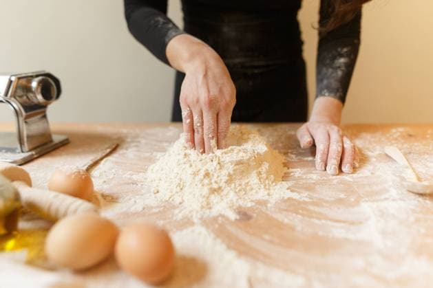IMAGO Creative: Clickbait, Rezepte und Kochen Anonymous person in black clothes making recess in flour mass with hand for adding eggs while cooking pastry for pasta at home Copyright: xValeriaxSchettinox Model Released