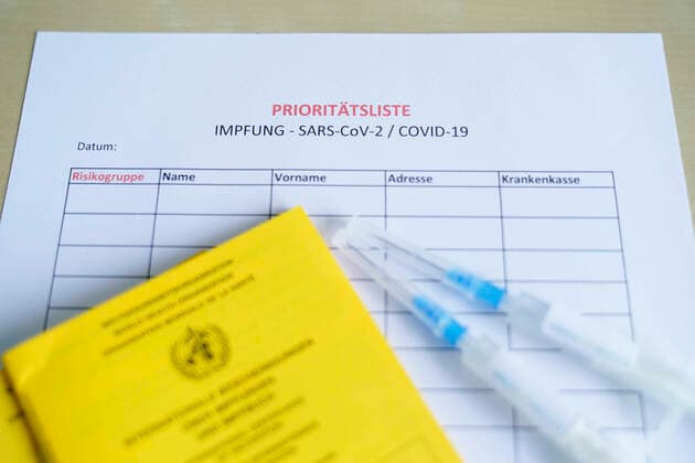 Symbol photo vaccination syringe Biontech and vaccination certificate Symbol photo of a waiting list and priority list of risk groups for vaccination with a BIONTECH vaccination syringe and vaccination certificate Germany