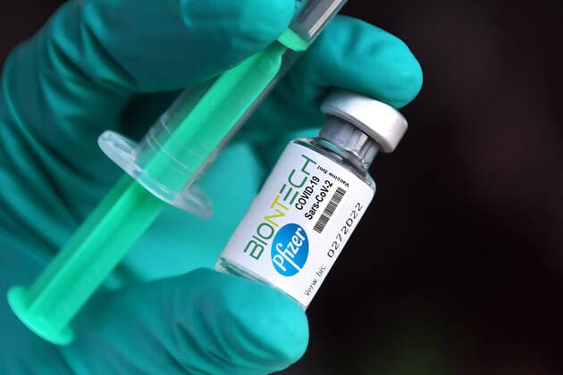 FOTOMONTAGE Theme image,symbol photo Vaccine from Biontech Pfizer before approval in Germany Medical personnel holding a vaccine syringe and a vaccine canister with vaccine against the coronavirus Vaccination with disposable syringe and vaccine for injection with a canula Hands in protective gloves