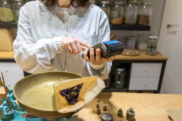 Crop unrecognizable woman holding terminal for payment in spice shop. Copyright: xx Model Released