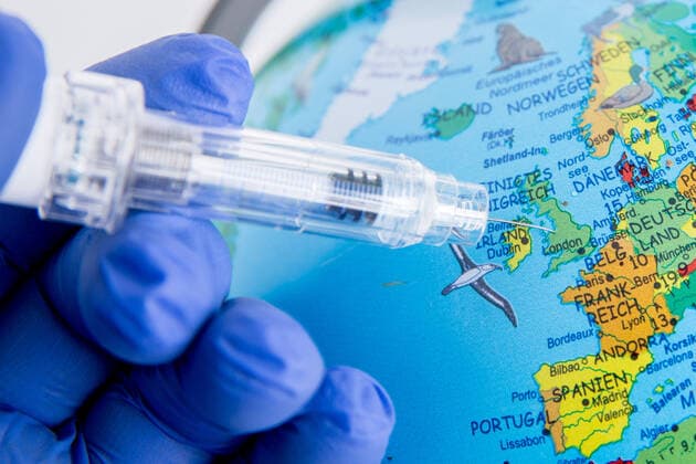 Bamberg, Germany 21 December 2020 A hand in rubber gloves holds a vaccination syringe, the needle of the vaccination syringe points on the globe to England, London Bavaria Copyright: xFotostandx xK.xSchmittx