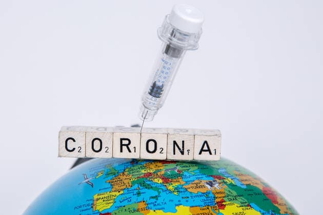 Bamberg, Germany 21 December 2020 A vaccination syringe is stuck in the lettering Corona, which lies on a globe, globe Bayern Copyright: xFotostandx xK.xSchmittx