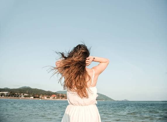 IMAGO Nature: Unsere Erde, Ressourcen, Wind Back view of woman standing at the ocean and adjusting hair in windy day in Thailand., Model released Copyright: xAlvaroxHernandezx MR