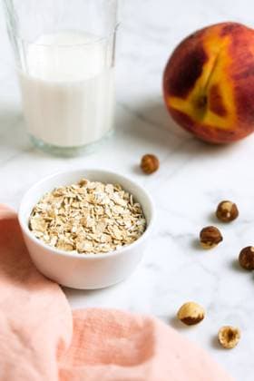 Oat bowl with hazelnuts, a glass of milk and a peach Copyright: xIvettexandxCox Model Released